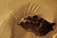 An ancient artifact partially buried in sand, glowing faintly under the sun.