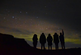 A group of people navigating using stars and a handmade map at night.