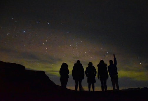 A group of people navigating using stars and a handmade map at night.