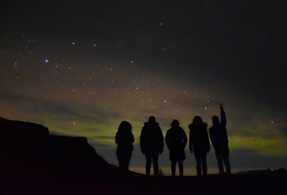 silhouette of five people under clear sky during night time