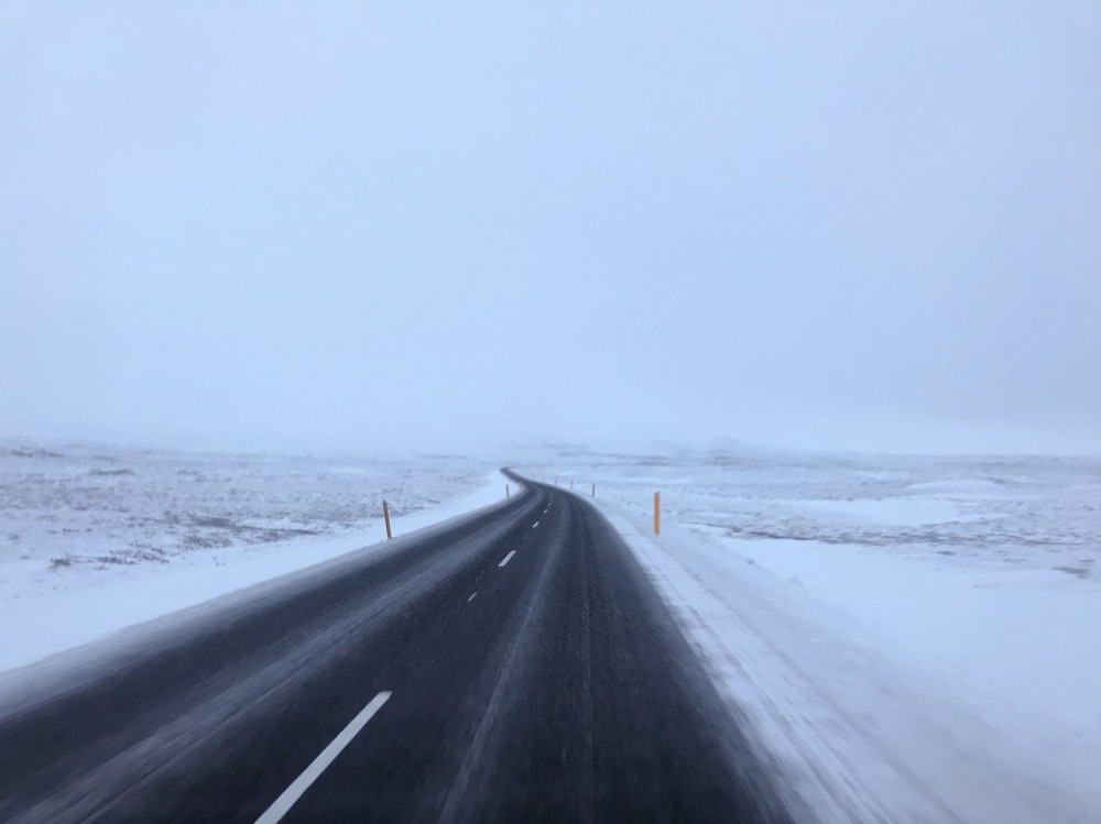 leere Straße zwischen schneebedecktem Land