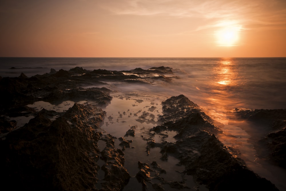 black rocks on seashore with sunset view