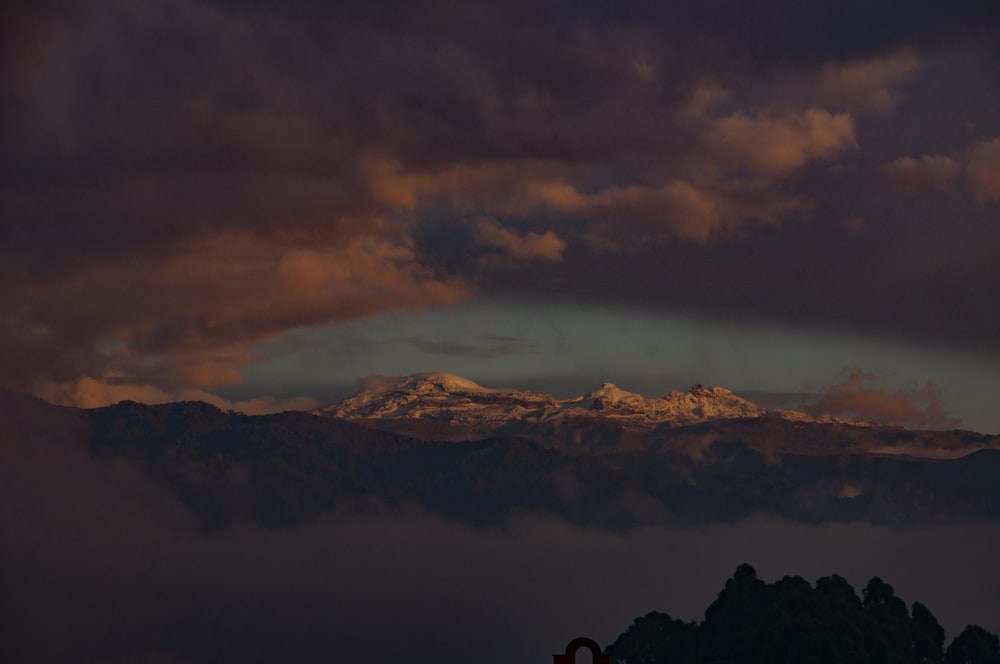 snow covered mountains under grey clouds