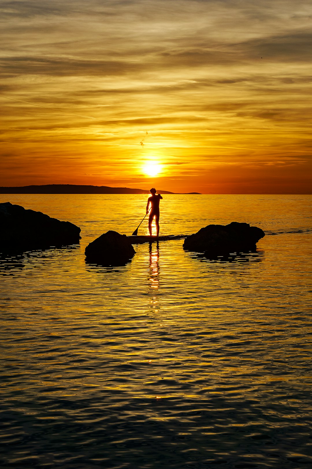 silhouette photography of man standing on paddleboard floating in ocean