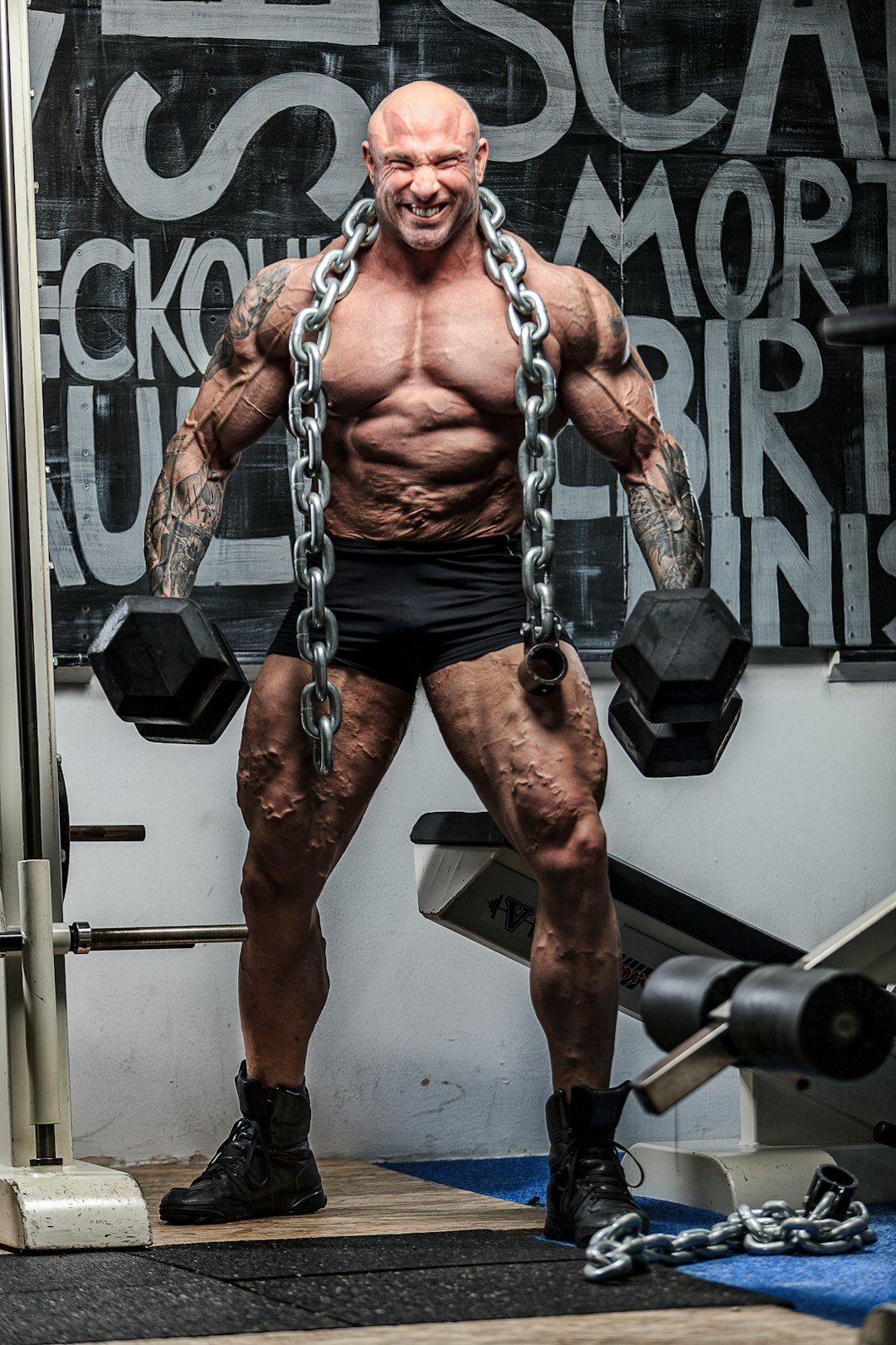 man holding two dumbbells and big chain on neck