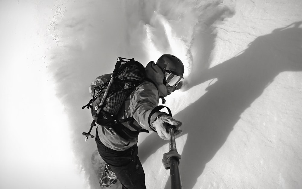 Mann im Schneewander-Outfit macht ein Selfie mit Einbeinstativ