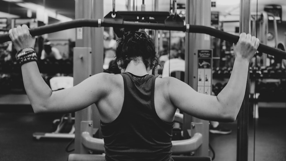 grayscale photography of woman holding lateral pull down machine