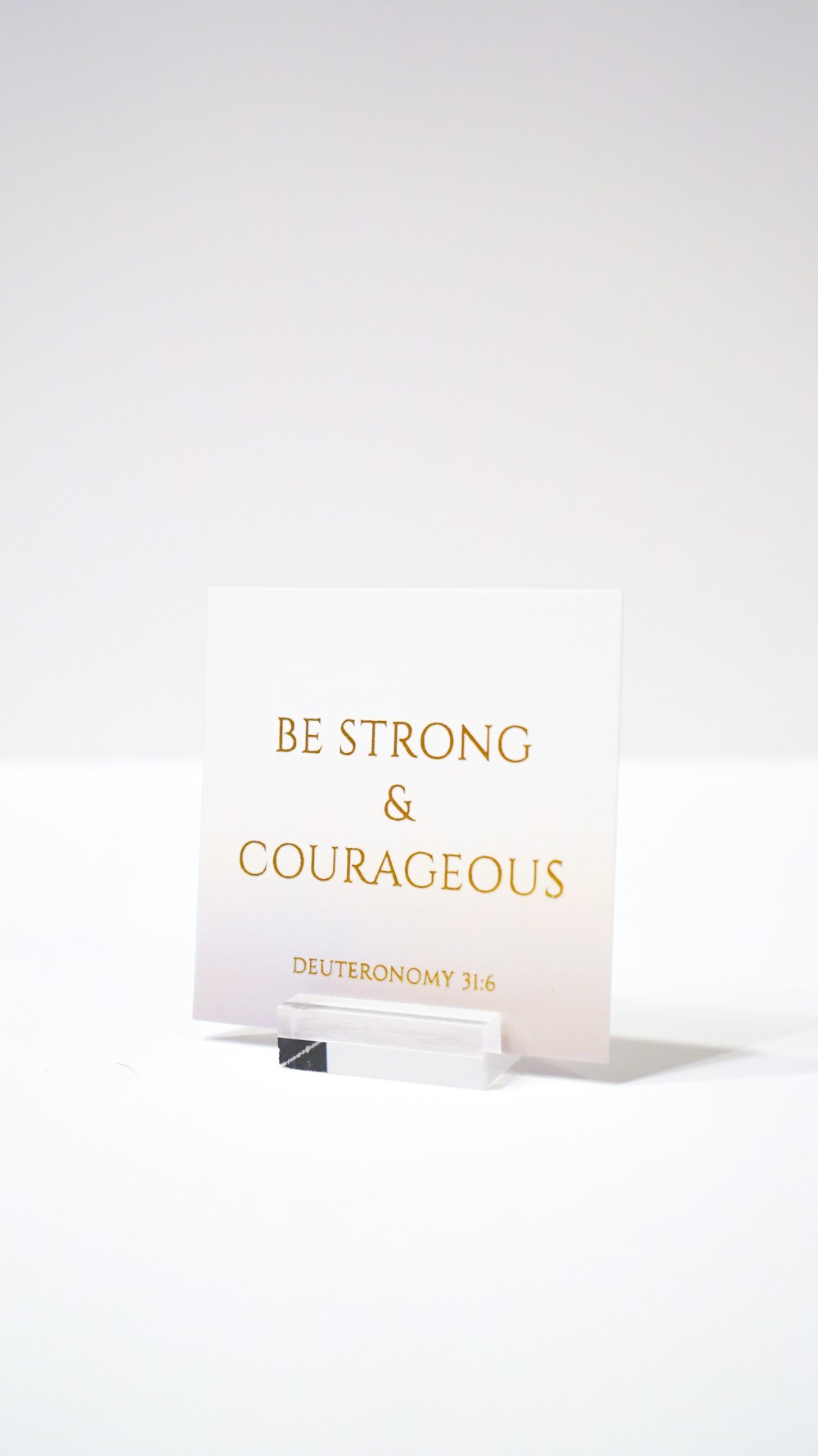 white paper with be strong and courageous printed text