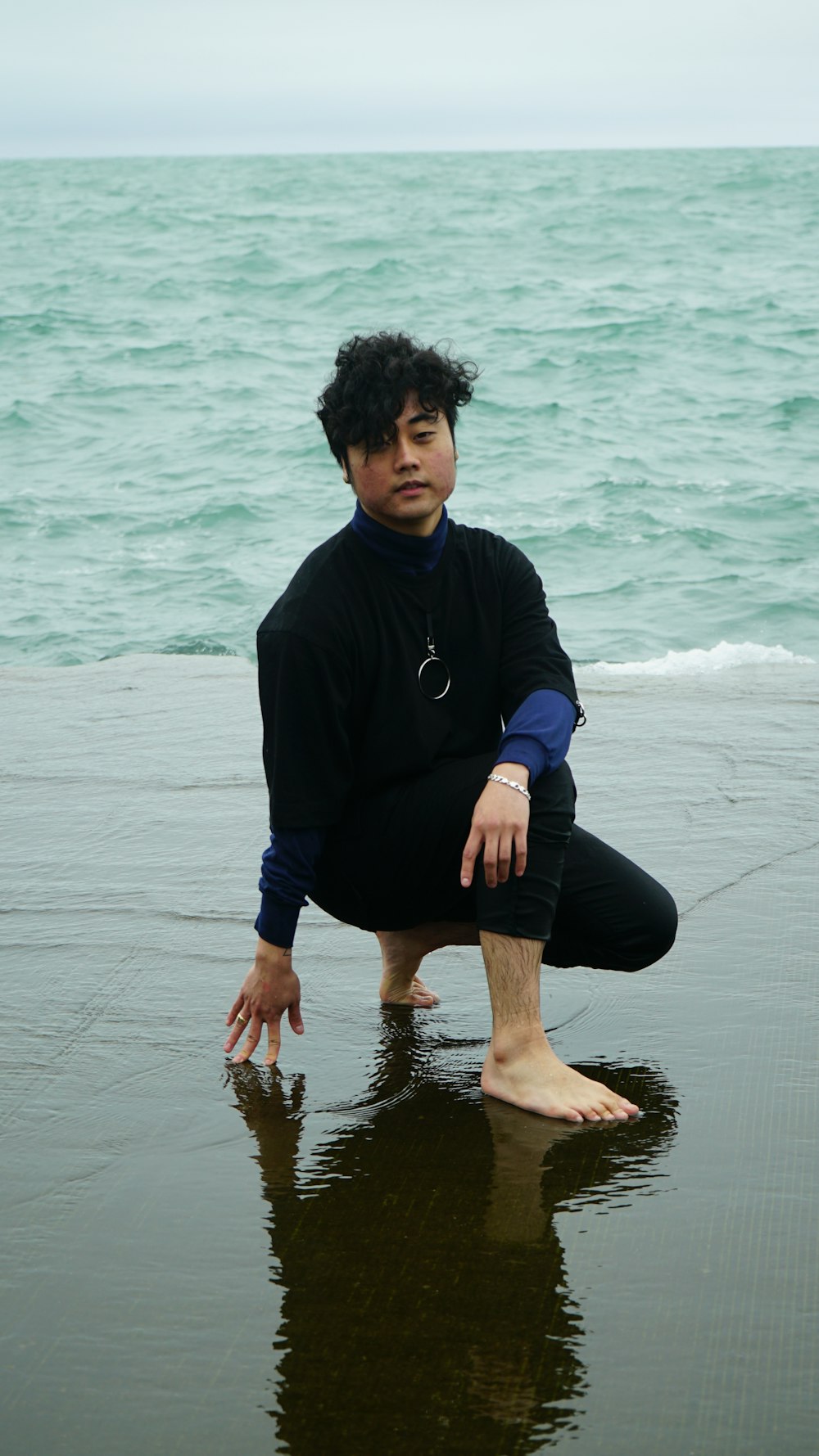 man kneeling on shore during daytime