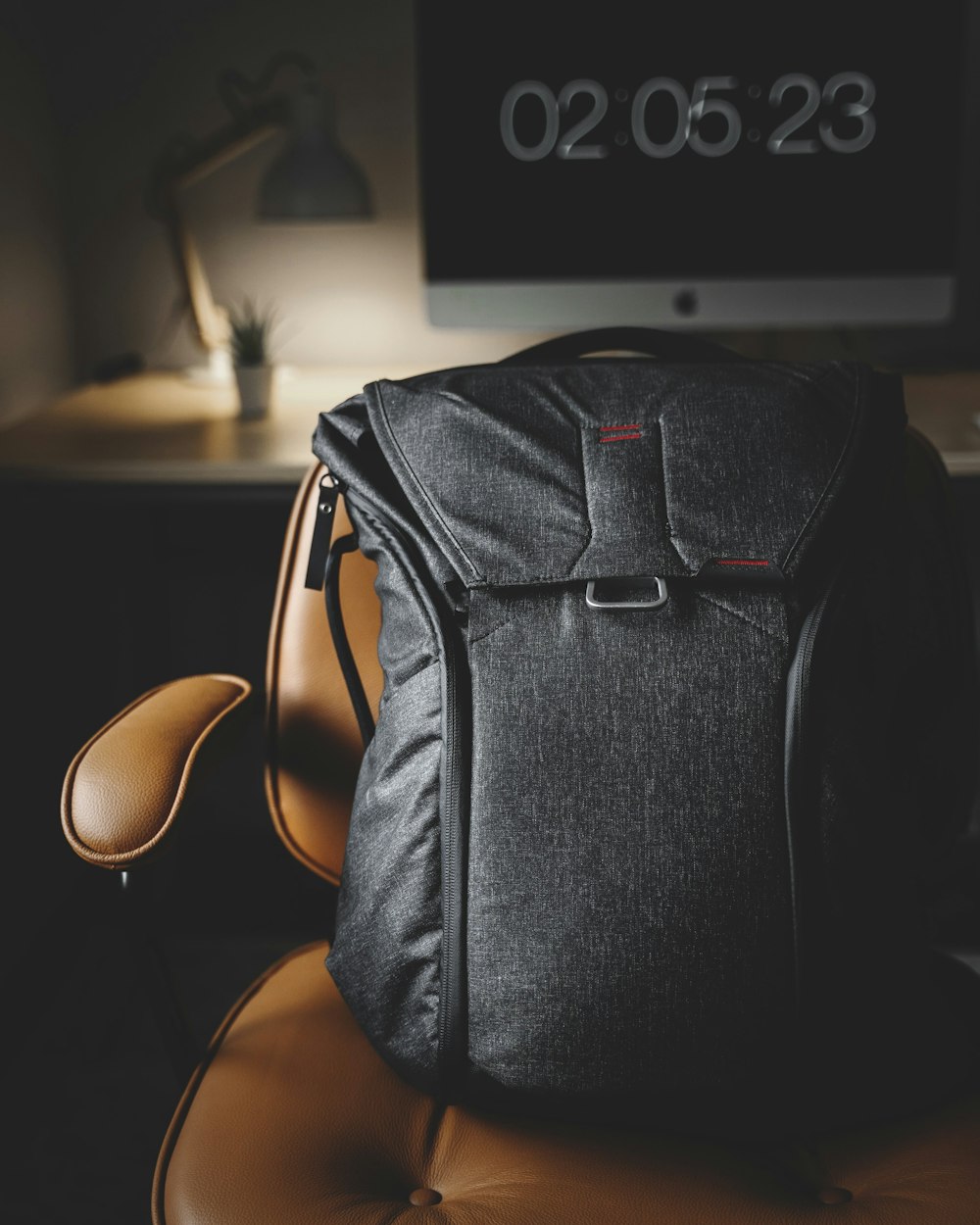 black backpack on brown leather armchair