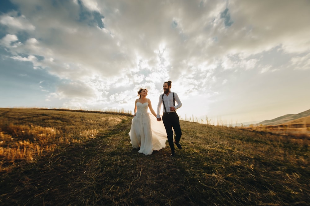 groom and bride running along grass field