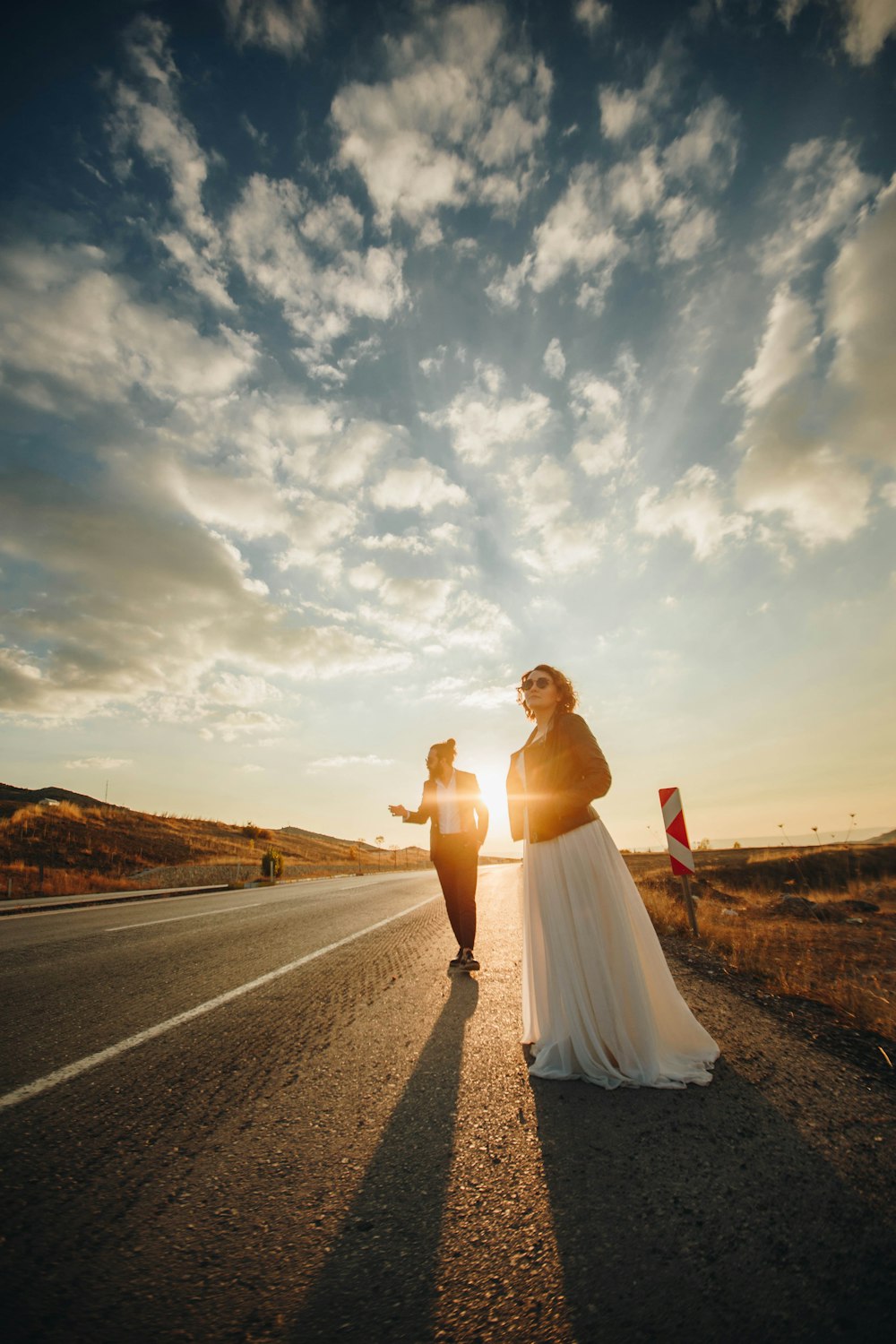 hombre y mujer de pie en el camino bajo cielos azules