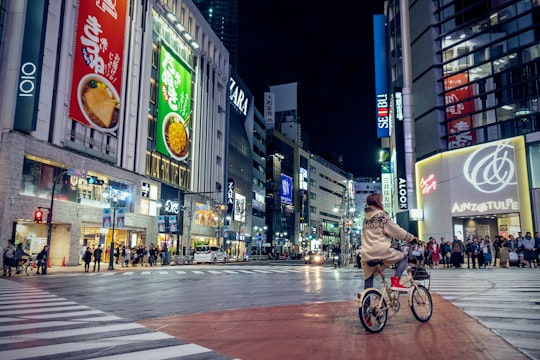woman riding bicycle in intersection at night in Shibuya-ku Japan