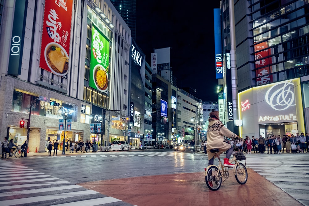 woman riding bicycle in intersection at night