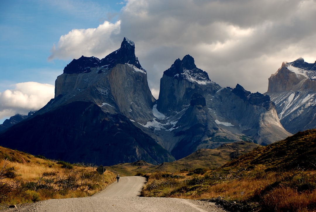 man walking on road front of mountain at daytime,