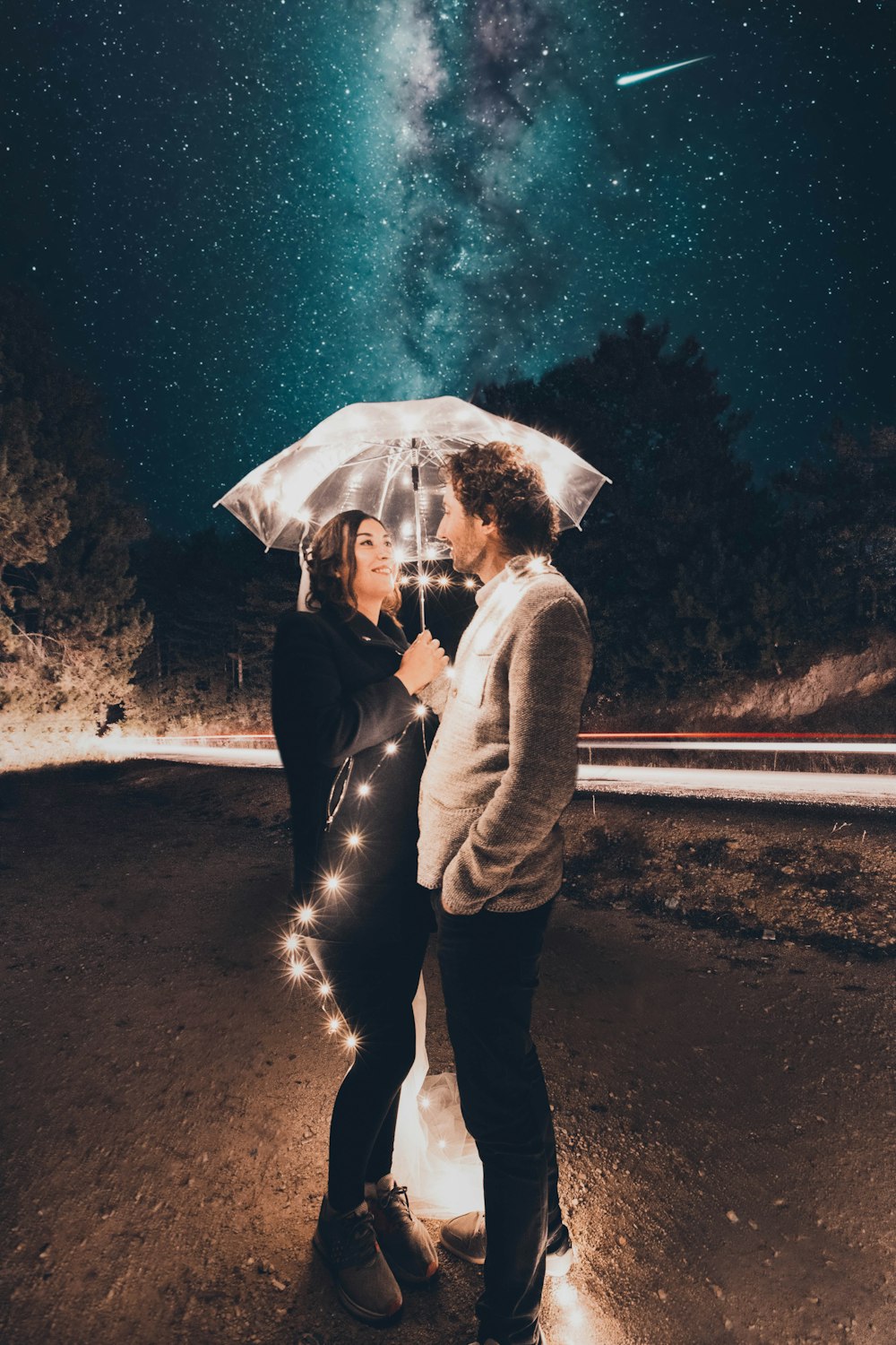 couple under clear umbrella with string lights during night