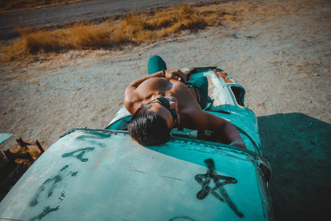 topless man lying on vehicle hood