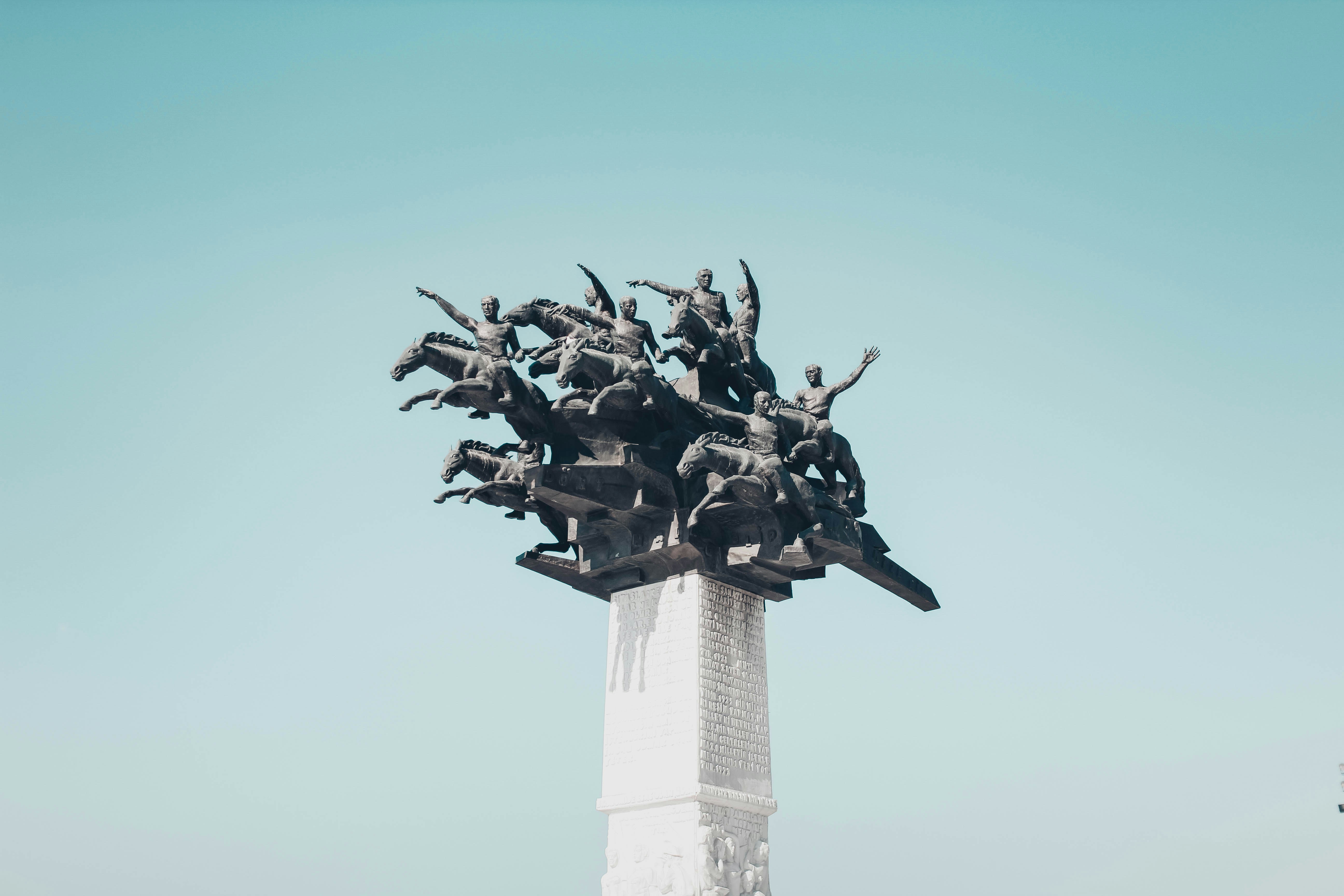 gray people riding horses statute under blue sky