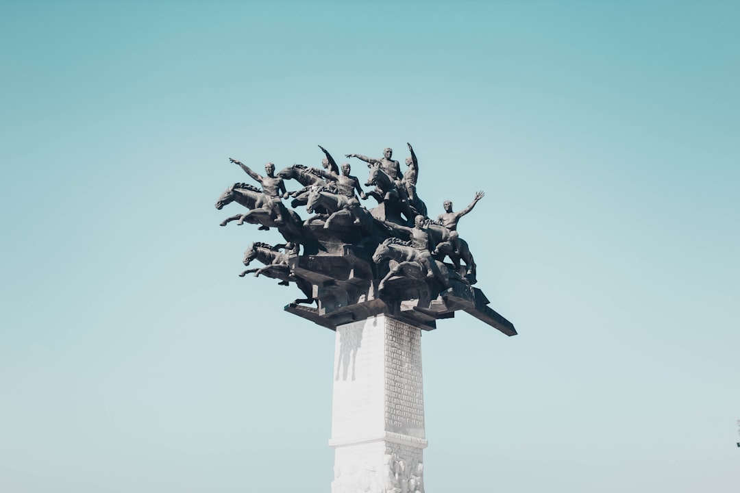 gray people riding horses statute under blue sky