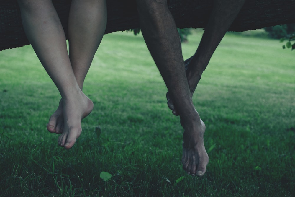 two persons sitting on tree trunk