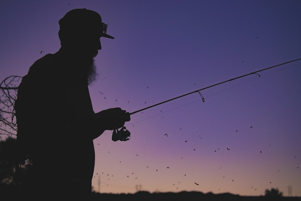 silhouette of man holding fishing rod
