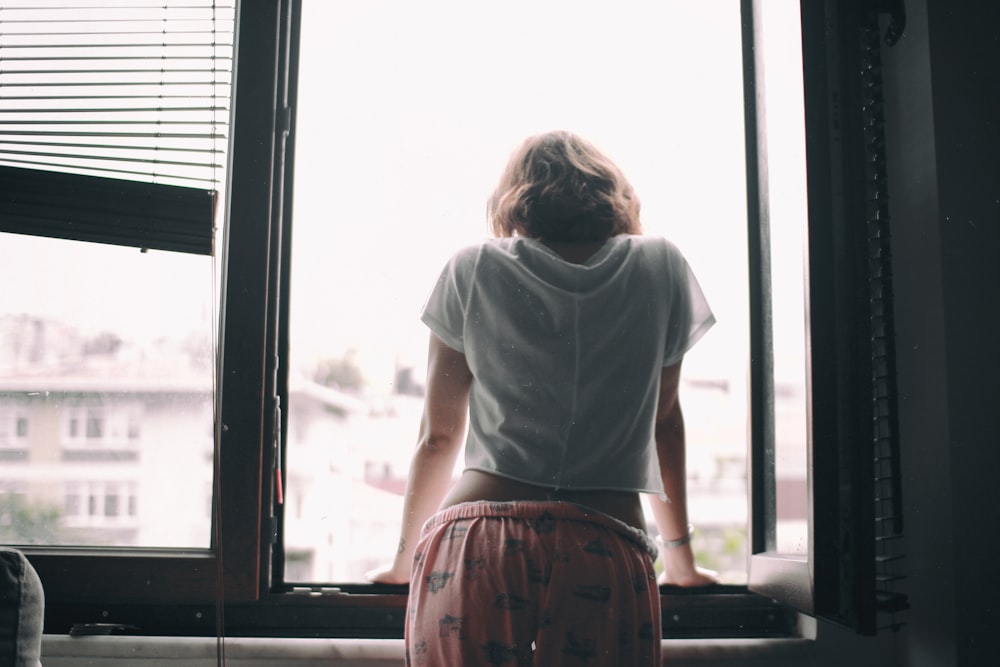 woman leaning on opened window at daytime