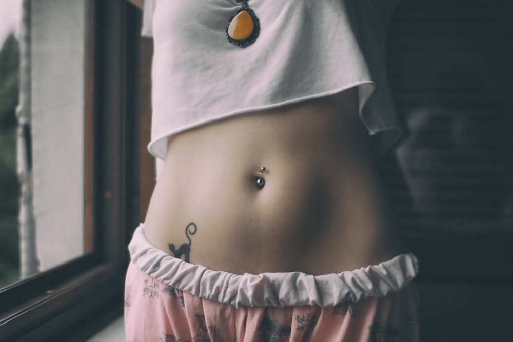 Frau im weißen Crop-Shirt mit Tattoo auf dem Bauch