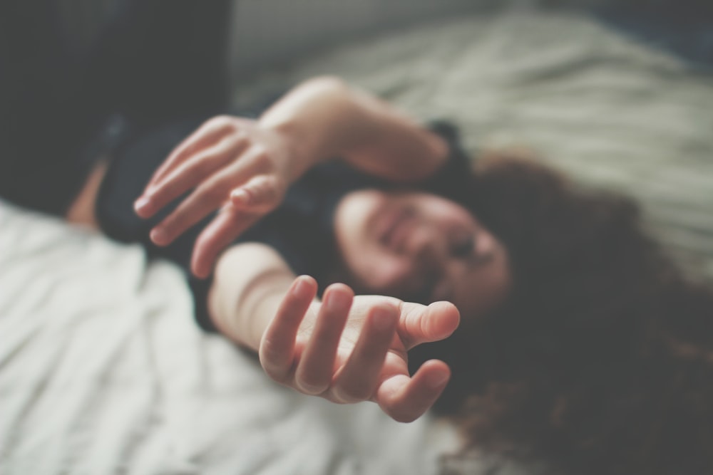 selective focus photography of woman lying bed