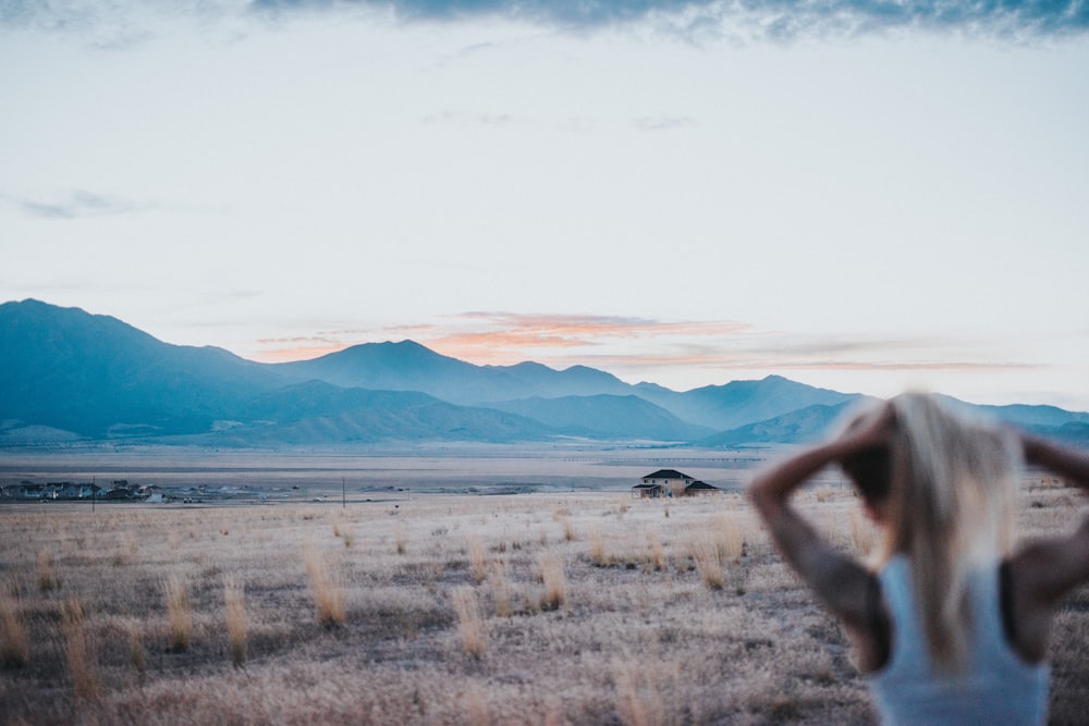 woman fixing her hair facing the field during day