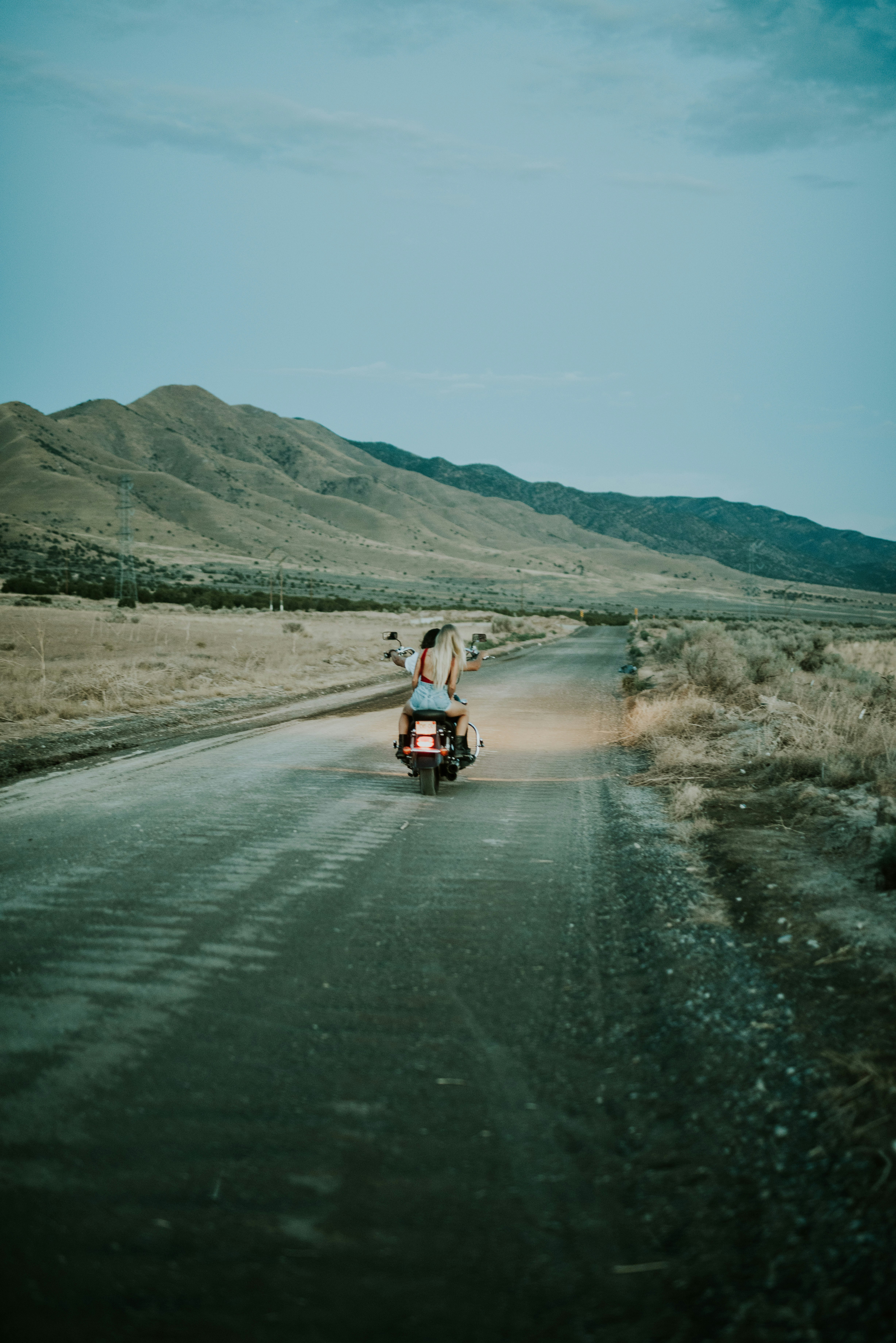 two person riding motorcycle on road viewing mountain