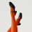 Black heeled shoes are paired with bright orange and red striped tights, with legs raised against a neutral background.