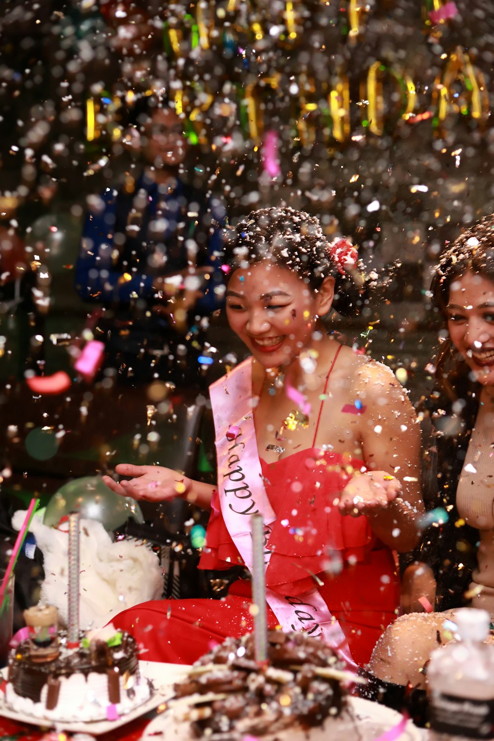 woman celebrating beside table with cakes and confetti