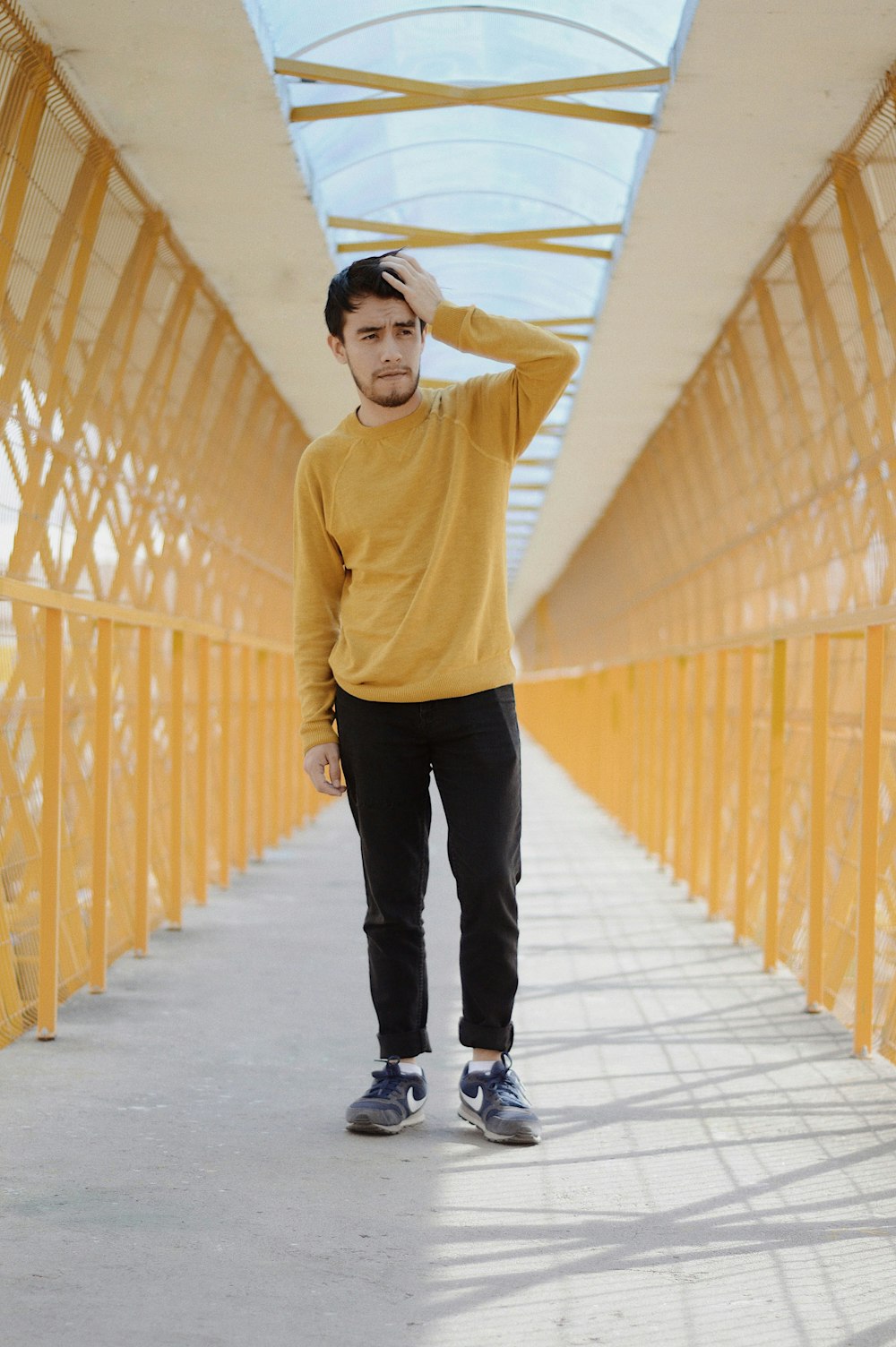 man standing on bridge while touching his head