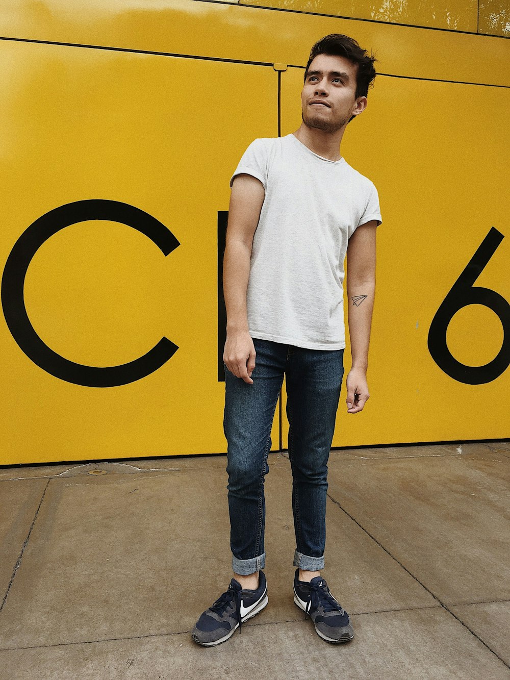 standing man wearing crew-neck t-shirt and blue denim jeans