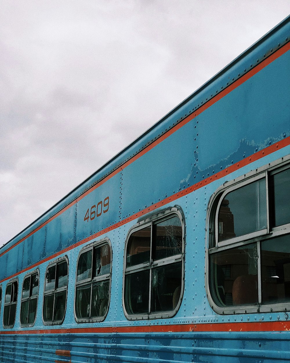 Train bleu et orange sous un ciel nuageux blanc pendant la journée