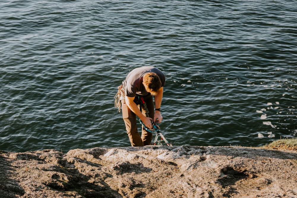 uomo in piedi sulla roccia vicino allo specchio d'acqua