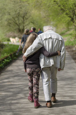 An adult and a child walking with arms around each other on a path