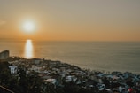 Coastal city skyline at sunset with buildings and sea.