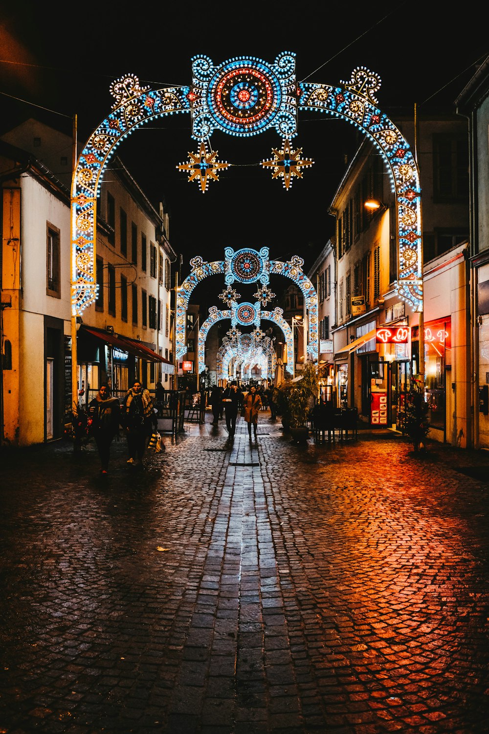 people standing between buildings at night