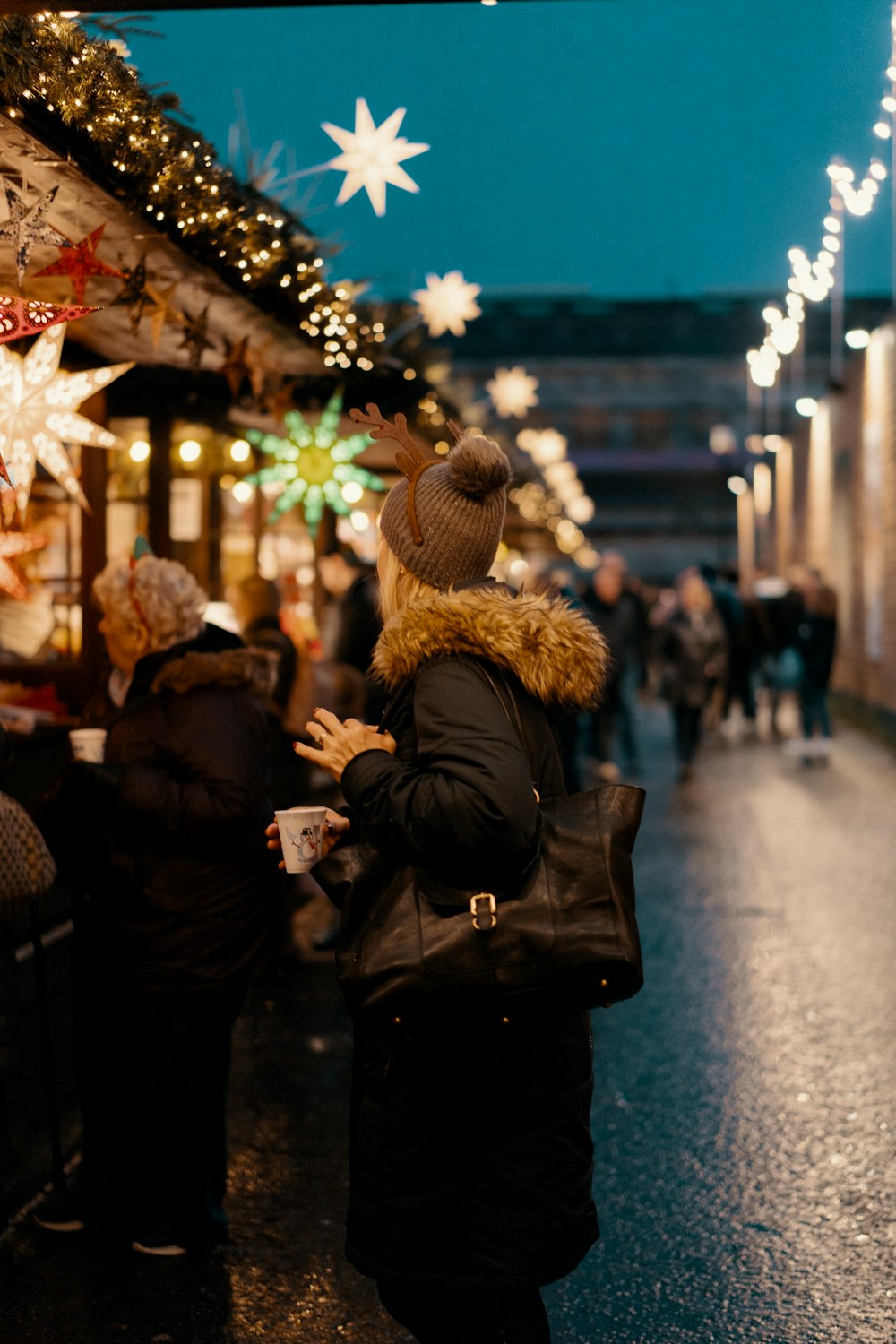 woman in black and brown furlined coat standing facing store