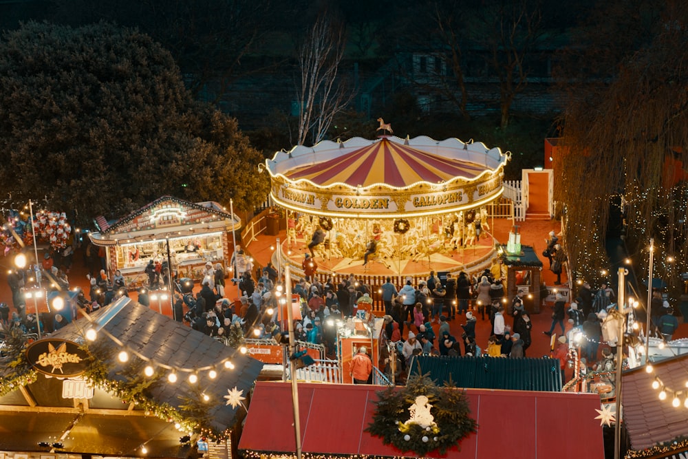 Personas de pie cerca del tiovivo en el parque de atracciones durante la noche