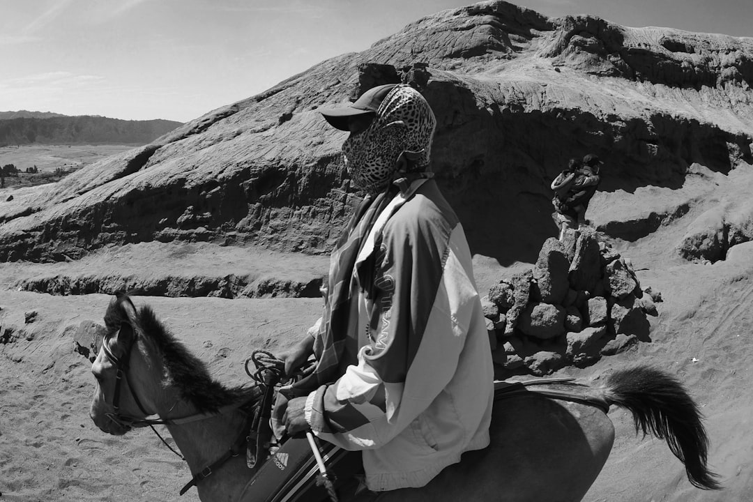 grayscale photography of man riding horse