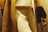 Close-up of a mannequin dressed in a beige coat with dark brown fur cuffs, cream-colored pants, and a light-colored shirt. The mannequin's hand is visible on the right side of the image.