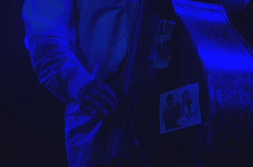 Close-up of a professional bassist playing electric bass in a dimly lit studio with warm lighting.