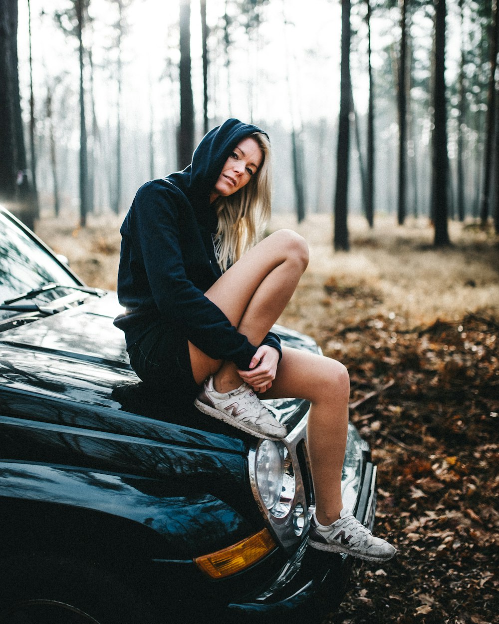 woman sitting on car hood during daytime