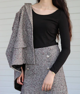 Flowy charcoal grey rousers with a subtle pleat detail, styled with a fitted black top and ankle boots.