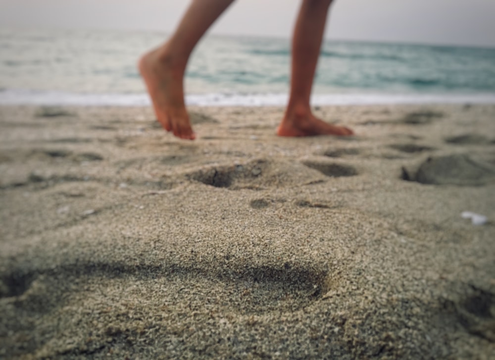 person walking on gray sands during daytime