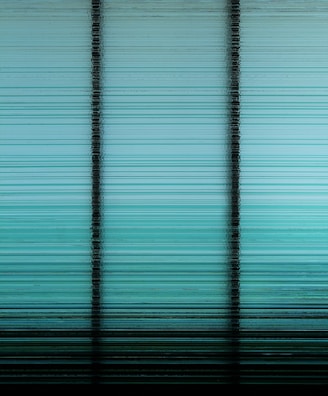 A digitally altered image with horizontal stripes forming a gradient from dark to light shades of teal and black, divided by vertical black lines implying a paneled structure.