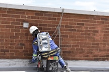 Professional inspecting rooftop structures using rope techniques