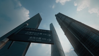 The towering Shanghai Tower piercing the sky, seen from street level with bustling city life.